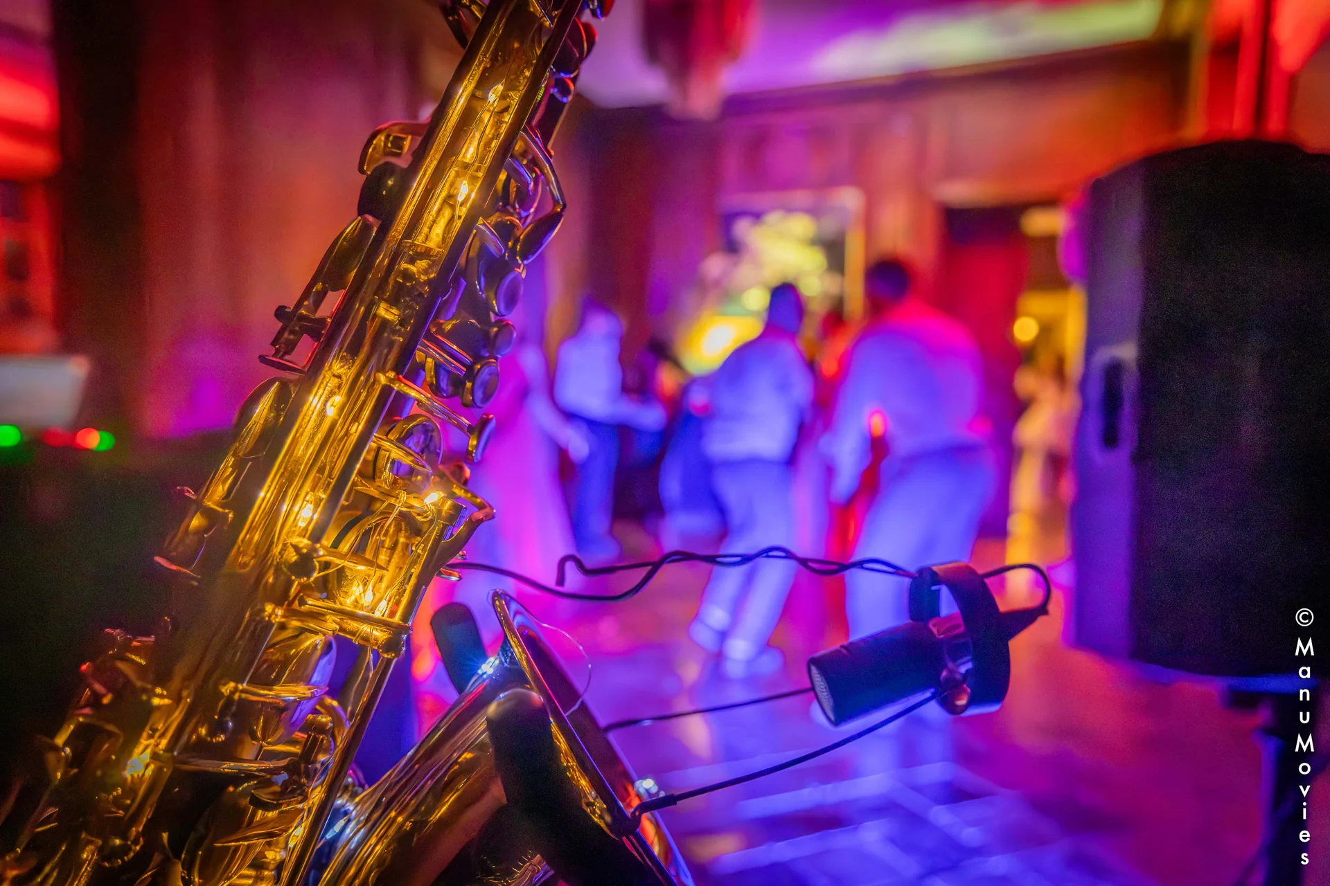 Saxophone doré et micro en gros plan, invités dansant en arrière-plan pendant une soirée DJ sax en Île-de-France