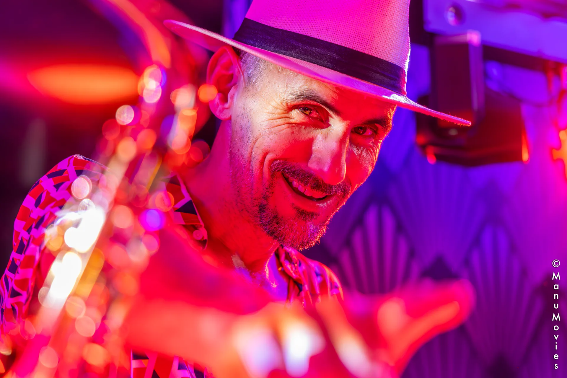 Portrait souriant de mikOsax, DJ saxophoniste, sous les lumières d'une soirée événementielle