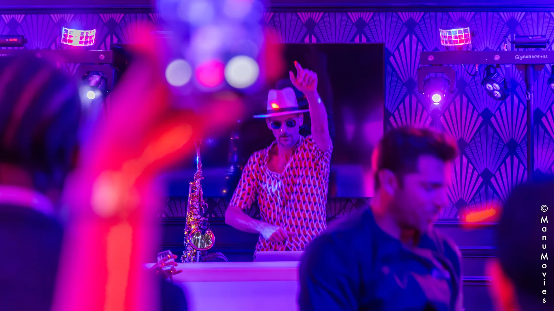 mikOsax, DJ sax, lève le bras derrière la console lors d'une soirée d'entreprise dans un décor Art déco à Paris