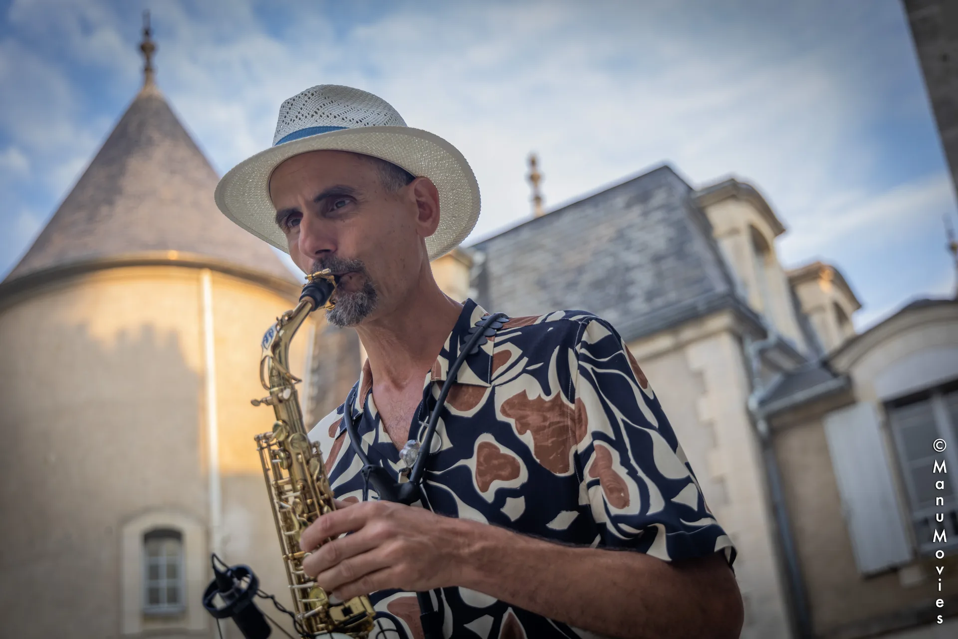 mikOsax, saxophonist in Paris, playing the alto saxophone in front of a French château at dusk